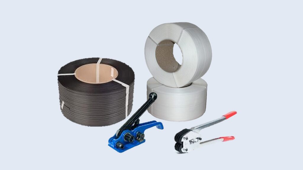 Bobinas de zuncho plástico negro y blanco junto a un tensador y un sellador manual